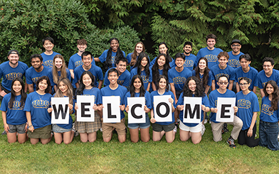 Future Global Leader students on the grassfield holding a welcome sign